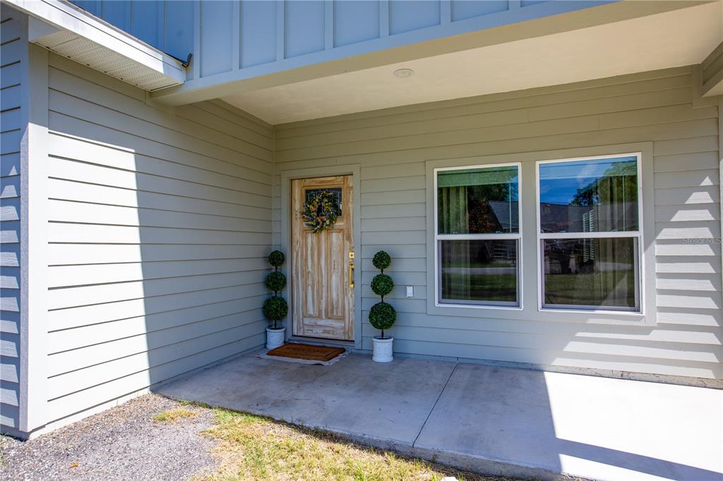 A light green house exterior features a wooden front door and two topiary plants — 991 NW 3RD STREET, LAKE BUTLER, FL