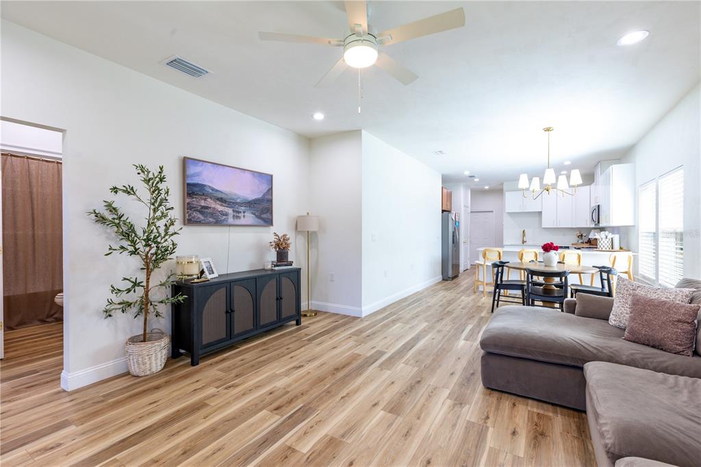 An open-concept living room and kitchen feature wood-look flooring, a ceiling fan, and white cabinetry — 991 NW 3RD STREET, LAKE BUTLER, FL