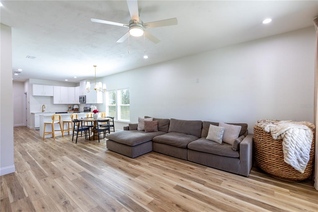 An open-concept living room and kitchen with wood-look flooring, a sectional sofa, and white cabinets — 991 NW 3RD STREET, LAKE BUTLER, FL