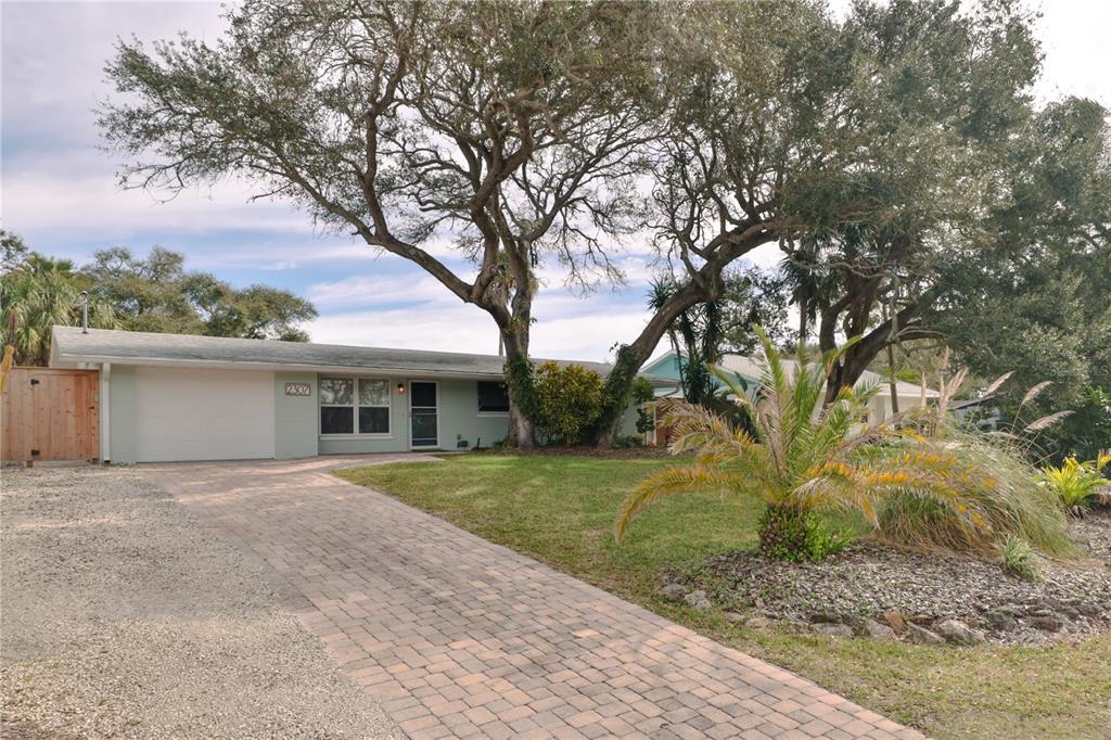 A single-story house with a paved driveway, a garage, and large trees in the yard — 2307 SAXON DRIVE, NEW SMYRNA BEACH, FL