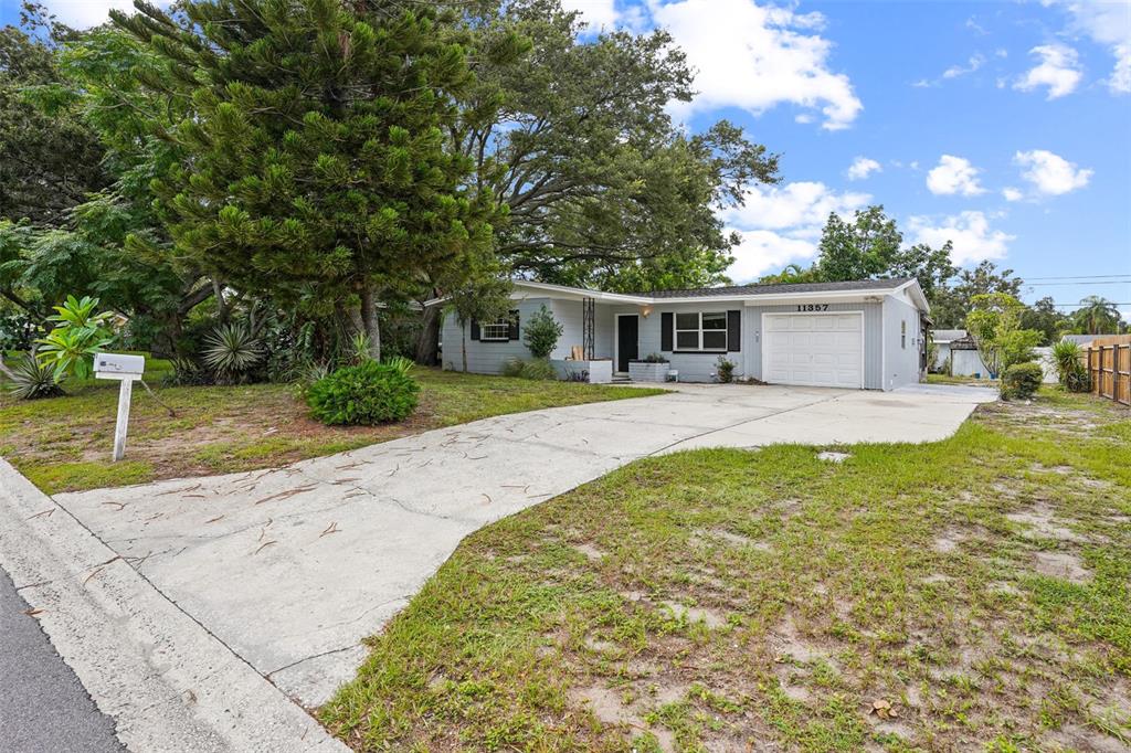 A single-story house with a white garage, gray siding, and a concrete driveway — 11357 116TH AVENUE, LARGO, FL