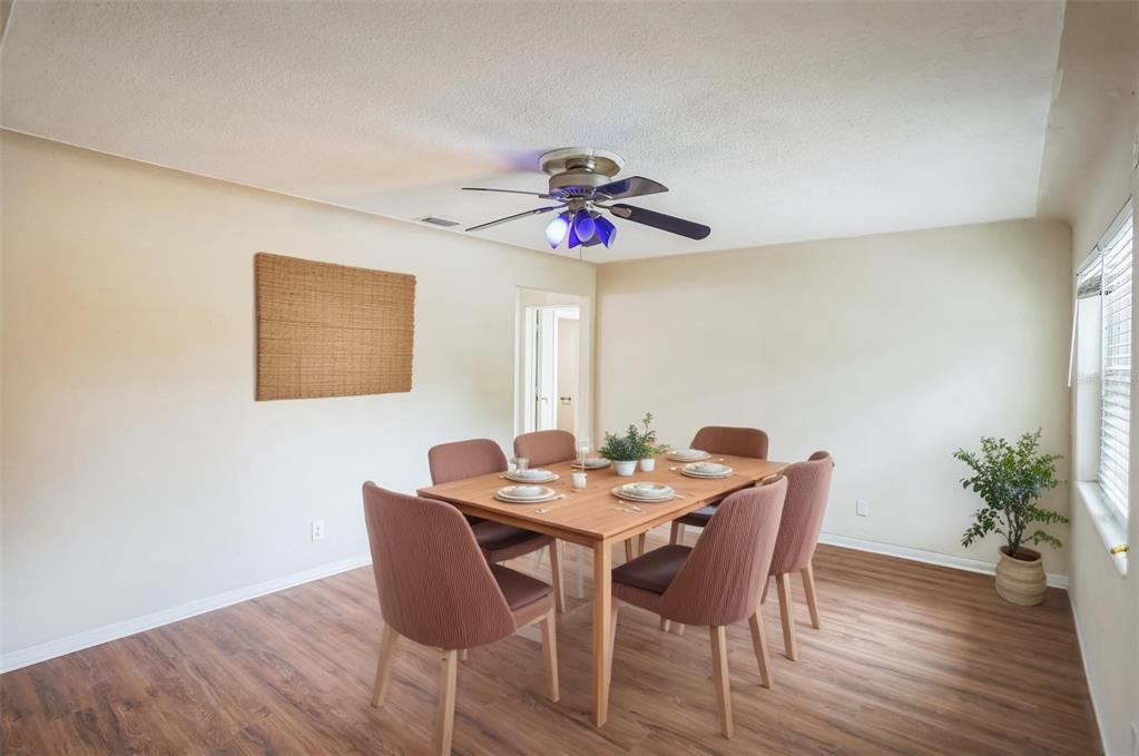 A dining room features a wooden table with six chairs, a ceiling fan, and wood flooring — 11357 116TH AVENUE, LARGO, FL