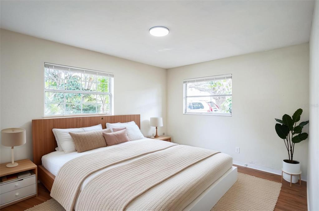 A bedroom features a bed with a wooden headboard, two windows, and a potted plant — 11357 116TH AVENUE, LARGO, FL