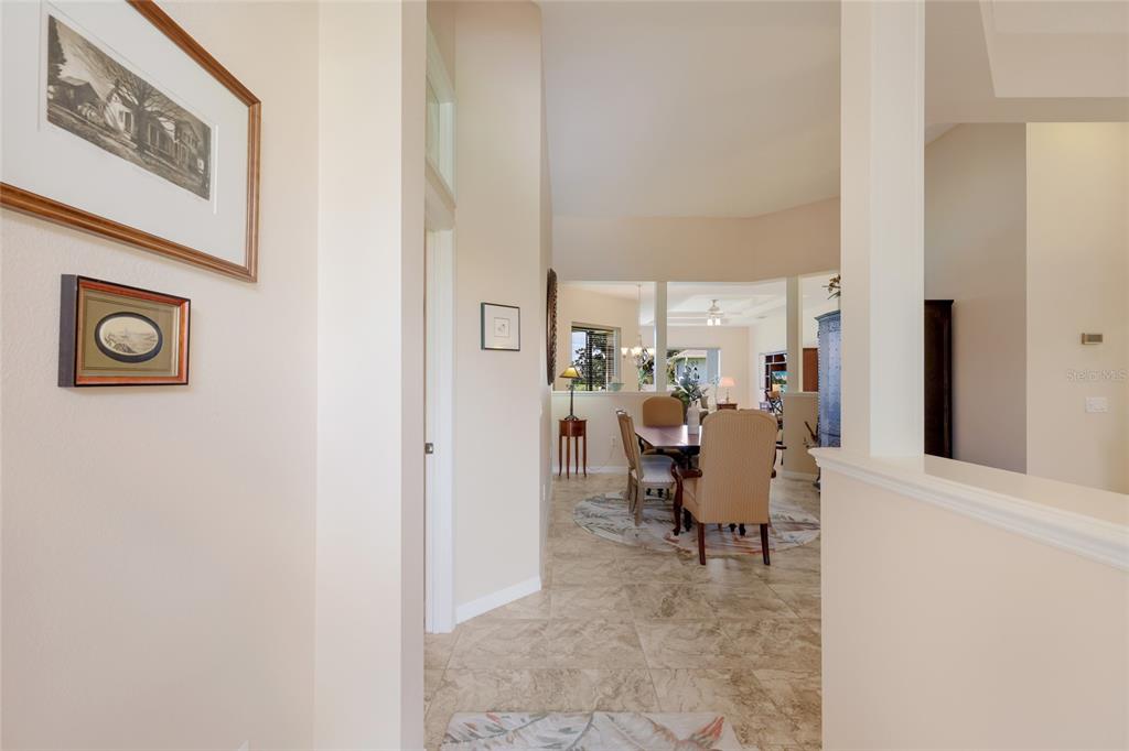 A view from a hallway looking into a dining area with tiled floors and high ceilings — 248 DAHLIA COURT, BRADENTON, FL