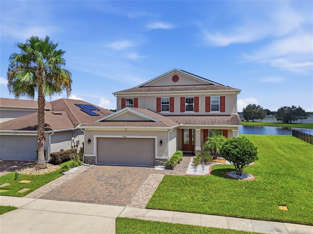 A two-story suburban house with a paved driveway, attached garage, and a pond in back — 2470 DAMMAR STREET, ORLANDO, FL