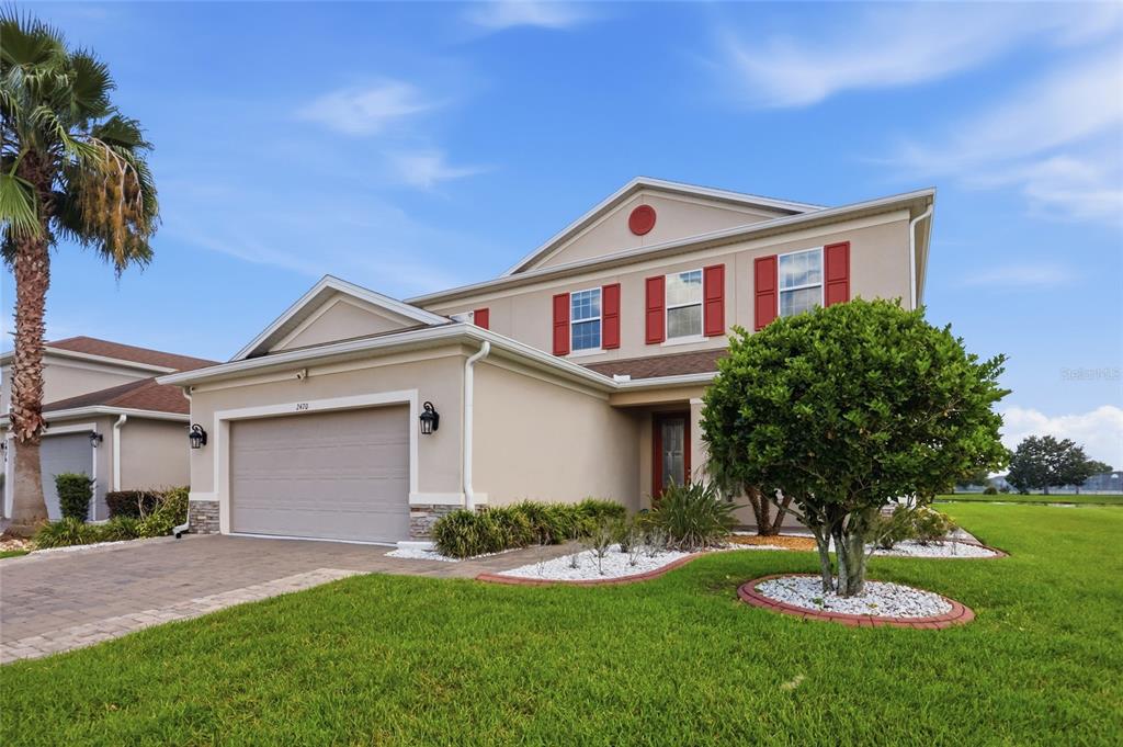 A two-story suburban house with a beige exterior, red shutters, and a paved driveway — 2470 DAMMAR STREET, ORLANDO, FL