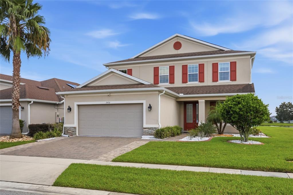 A two-story suburban house with a beige stucco exterior, red shutters, and a paved driveway — 2470 DAMMAR STREET, ORLANDO, FL