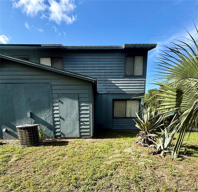 The exterior of a two-story house features blue horizontal siding, a door, and an air conditioner — 753 SW 2ND TERRACE, GAINESVILLE, FL