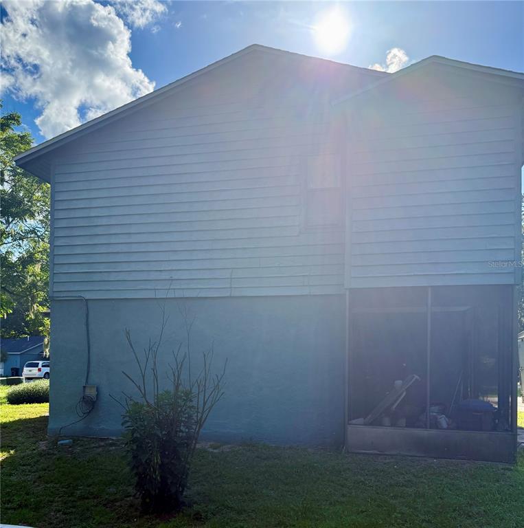 The exterior of a two-story house features light-colored siding, a stucco base, and a screened-in porch — 753 SW 2ND TERRACE, GAINESVILLE, FL