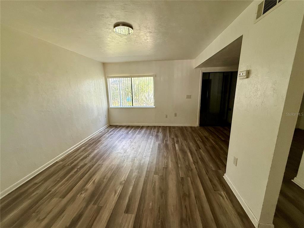 An empty room features light-colored walls, a single window, and wood-look flooring — 753 SW 2ND TERRACE, GAINESVILLE, FL