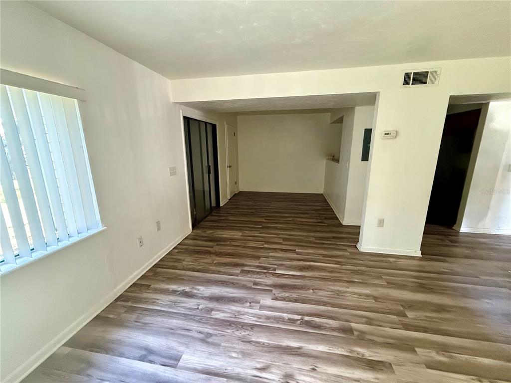 An interior view shows a room with wood-look flooring, white walls, and a window with blinds — 753 SW 2ND TERRACE, GAINESVILLE, FL