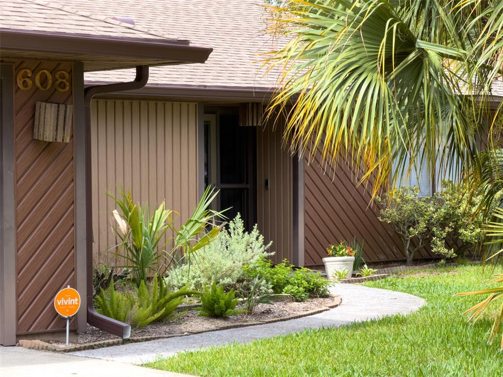 A brown house exterior features diagonal wood siding, a front walkway, and a Vivint sign — 608 TOUCHSTONE CIRCLE, PORT ORANGE, FL