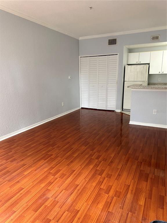 An interior view shows a room with wood-look flooring, a white closet, and a kitchen — 6384 RALEIGH STREET UNIT 2203, ORLANDO, FL
