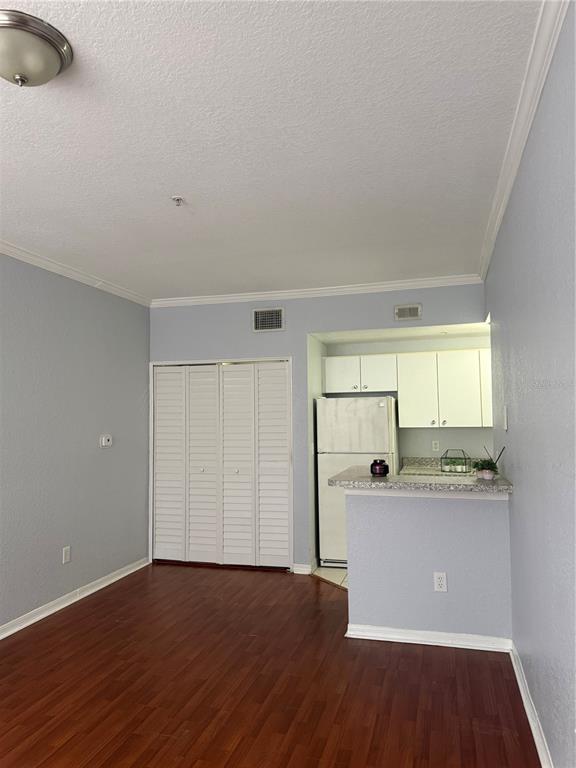 A kitchen with white cabinets and a breakfast bar opens into a room with wood floors — 6384 RALEIGH STREET UNIT 2203, ORLANDO, FL
