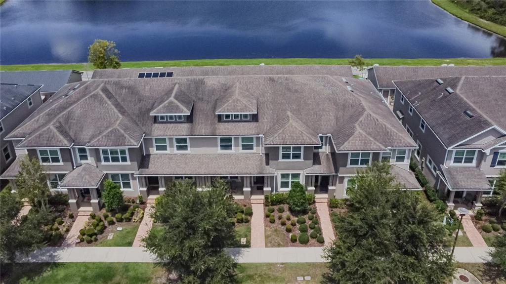 An aerial view shows a multi-unit townhouse building with a shingled roof near a lake — 8415 LOVETT AVENUE, ORLANDO, FL