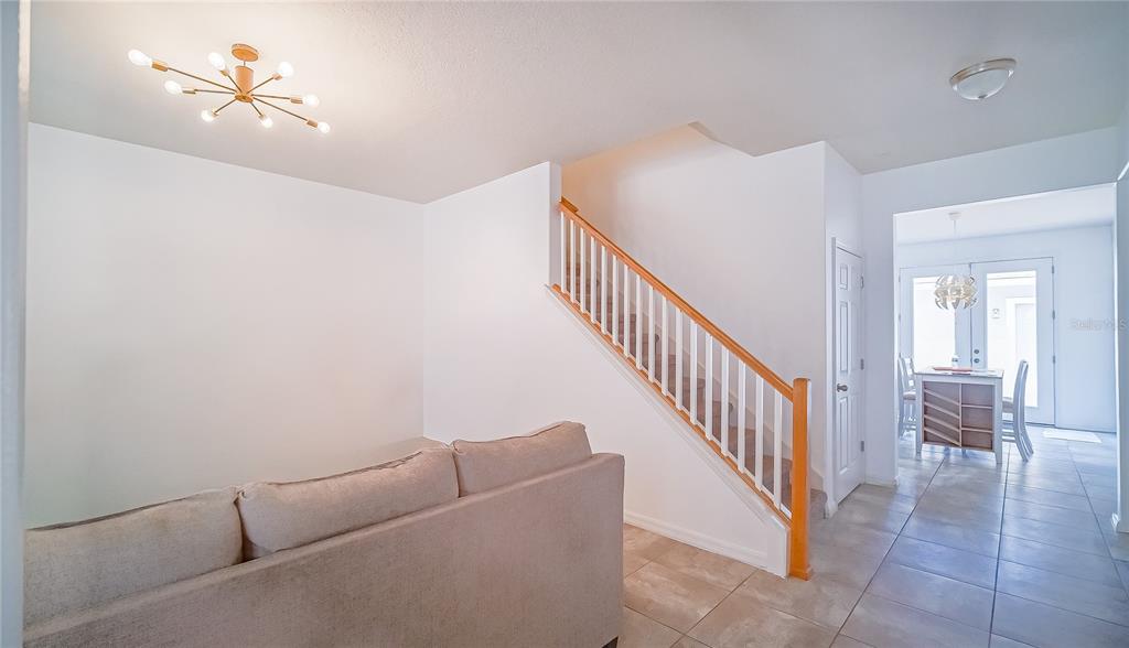 A living area with a sofa, a staircase with wooden railings, and a tiled dining area — 8415 LOVETT AVENUE, ORLANDO, FL