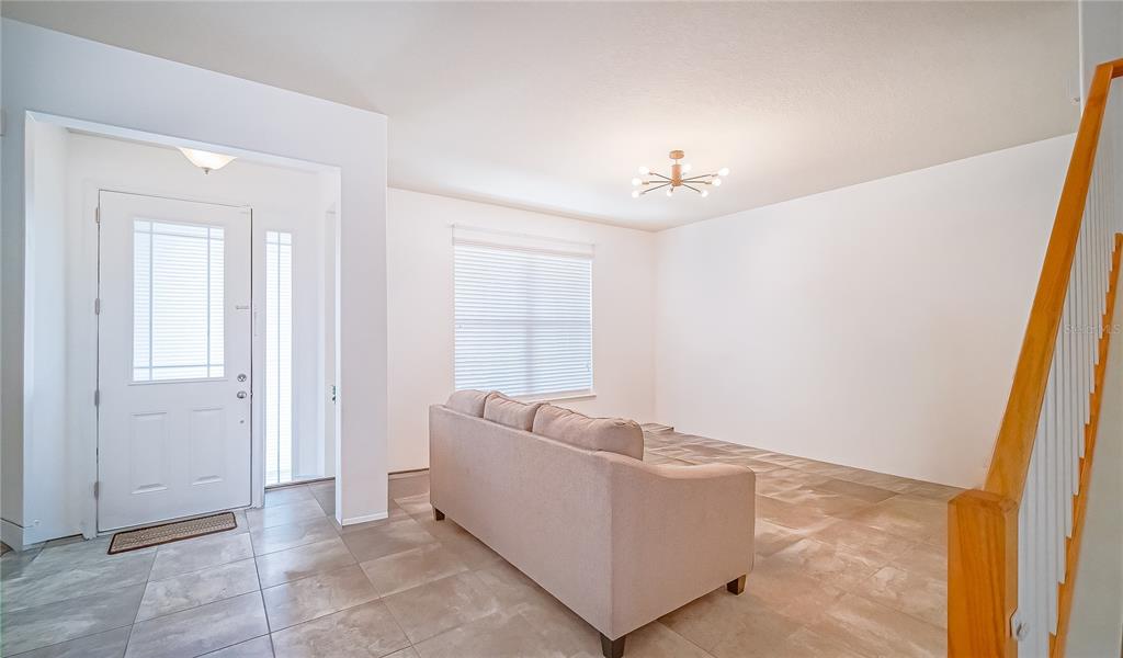 A living room features light tile flooring, a beige sofa, and a modern sputnik chandelier — 8415 LOVETT AVENUE, ORLANDO, FL