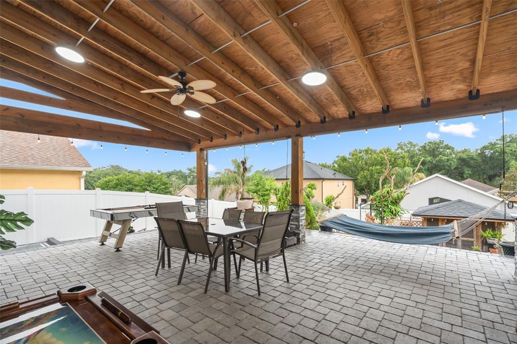 A covered outdoor patio features a dining set, a pool table, and a hanging hammock — 2408 CIMMARON ASH WAY, APOPKA, FL