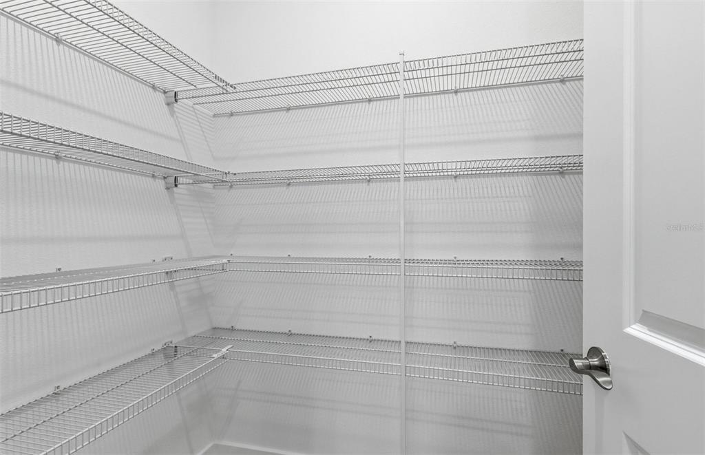 A walk-in pantry featuring white walls and multiple levels of white wire shelving — 37253 GUNNISON DRIVE, ZEPHYRHILLS, FL