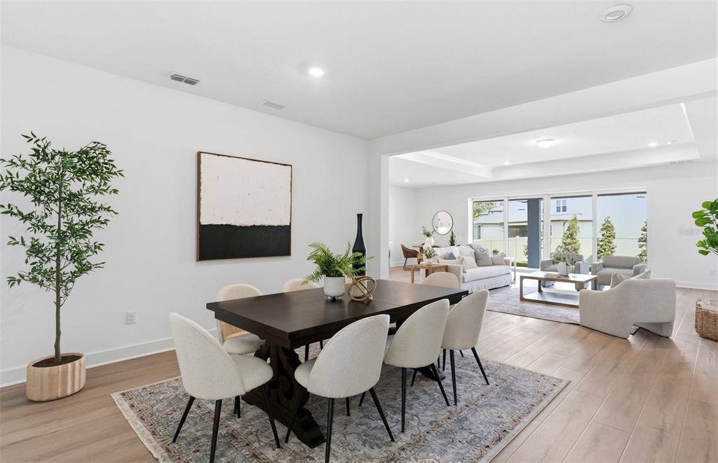 A dining area with a dark wood table and light chairs opens into a living room — 37253 GUNNISON DRIVE, ZEPHYRHILLS, FL