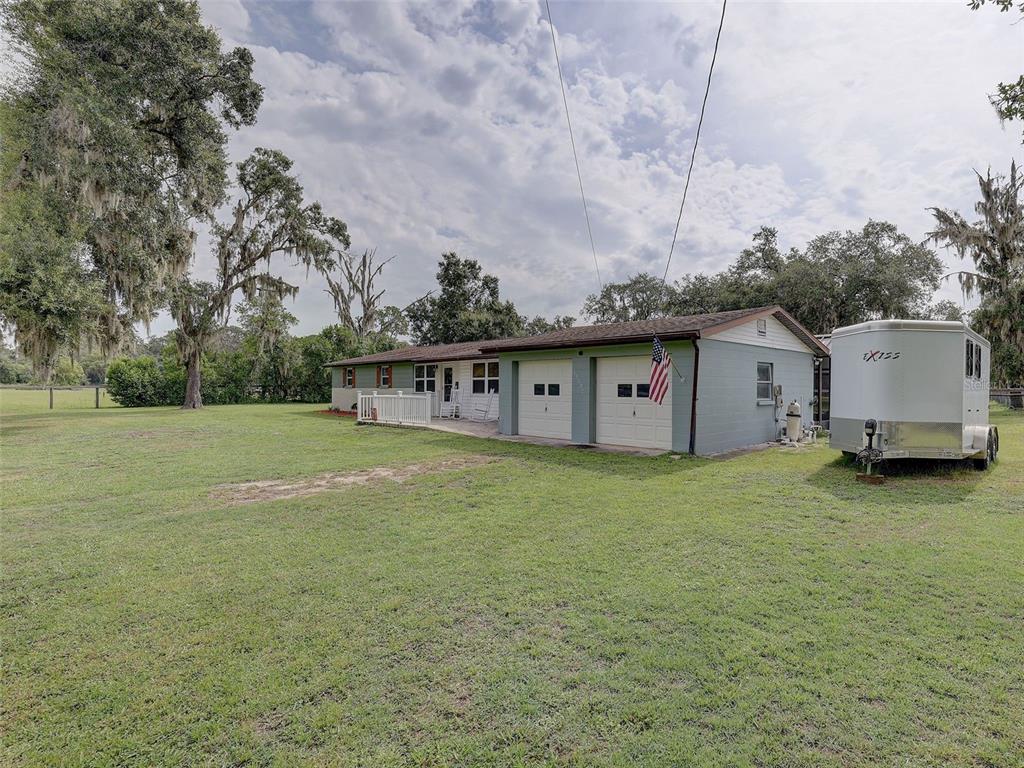 A single-story house with a two-car garage and a horse trailer parked on the lawn — 13102 GIBSON LANE, ODESSA, FL