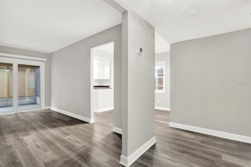 An interior view shows a living area with gray wood-look flooring and a sliding door — 8345 13TH STREET N UNIT B, ST PETERSBURG, FL