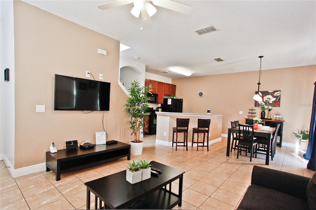 An open-concept living and dining area features tile flooring, a kitchen island, and neutral walls — 4577 ALBERTO CIRCLE, KISSIMMEE, FL