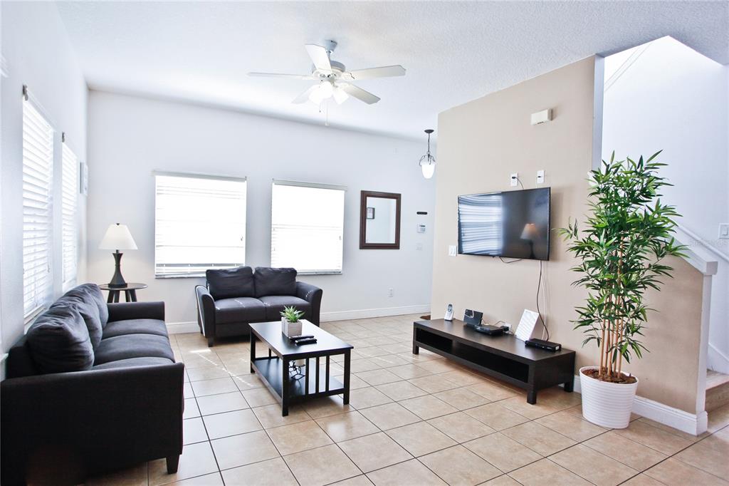 A living room features tile flooring, a dark sofa set, a television, and a potted plant — 4577 ALBERTO CIRCLE, KISSIMMEE, FL