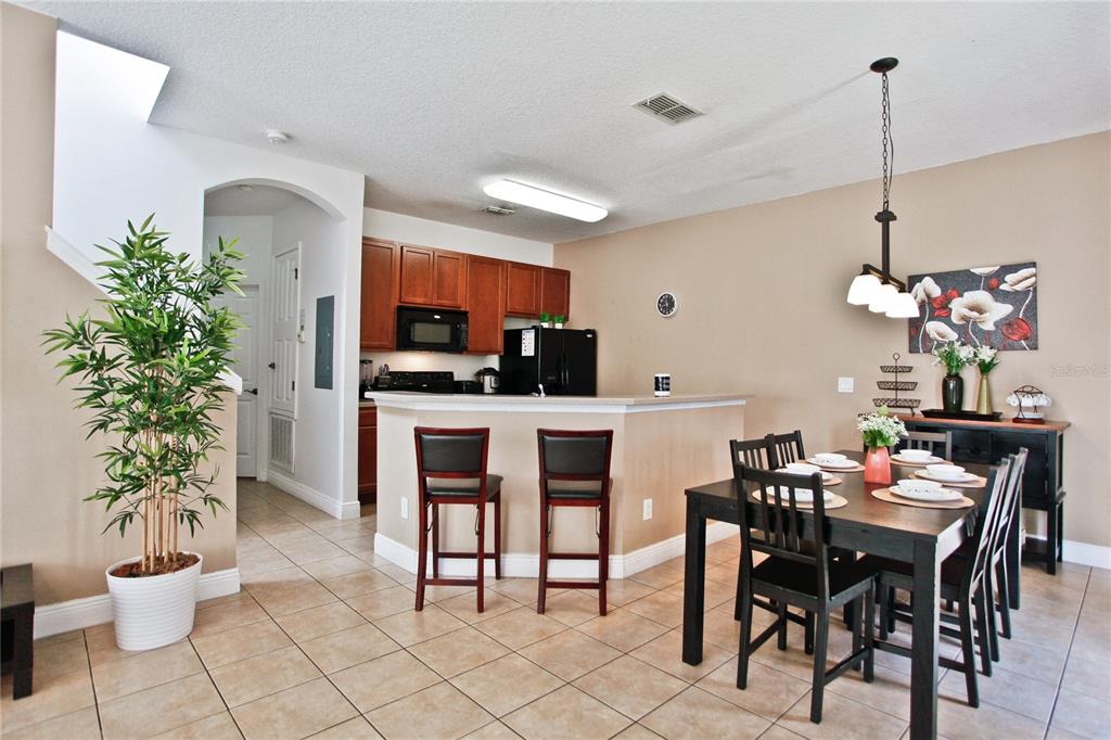 A dining area and kitchen with tile floors, a breakfast bar, and dark wood cabinetry — 4577 ALBERTO CIRCLE, KISSIMMEE, FL
