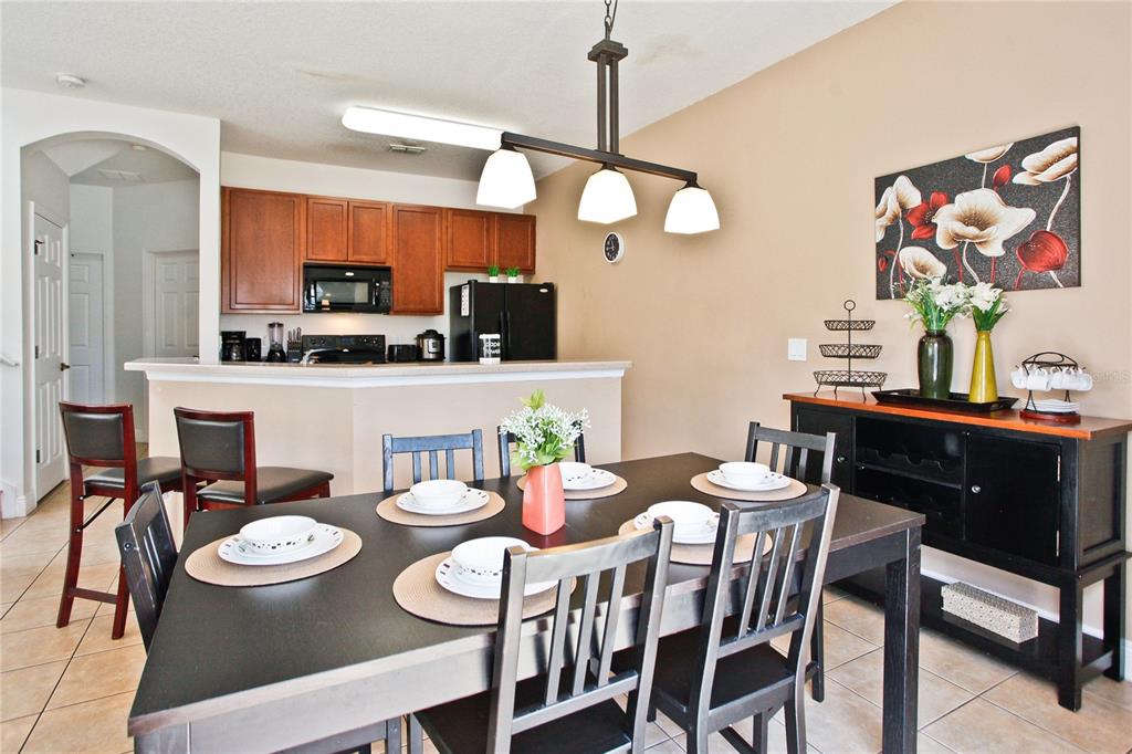 A dining area with a dark table and chairs sits in front of an open kitchen — 4577 ALBERTO CIRCLE, KISSIMMEE, FL