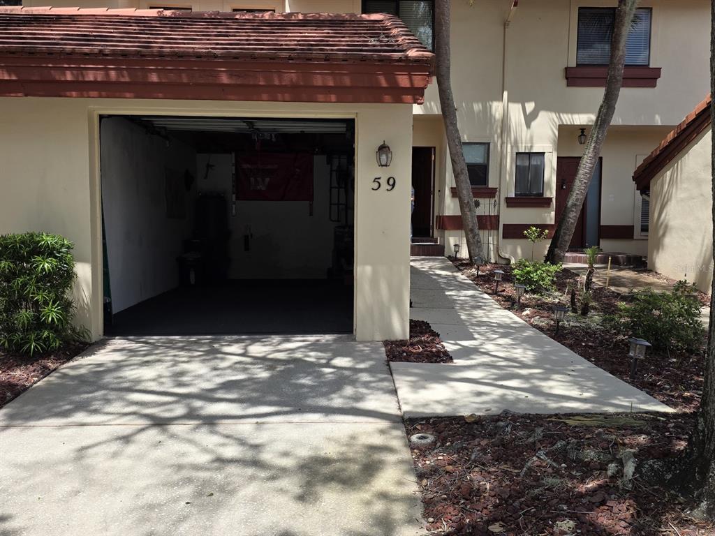 The exterior of a townhouse features a one-car garage, a concrete walkway, and a front entrance — 3460 COUNTRYSIDE BOULEVARD UNIT 59, CLEARWATER, FL