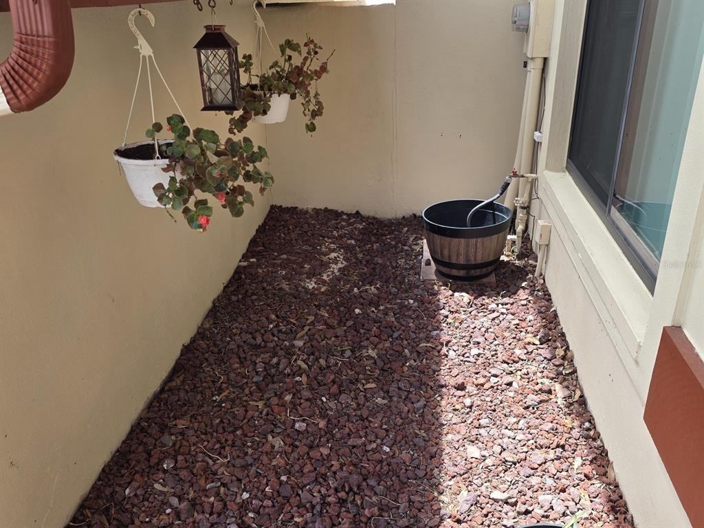 A small outdoor patio area features reddish-brown gravel, hanging plants, and a wooden barrel planter — 3460 COUNTRYSIDE BOULEVARD UNIT 59, CLEARWATER, FL