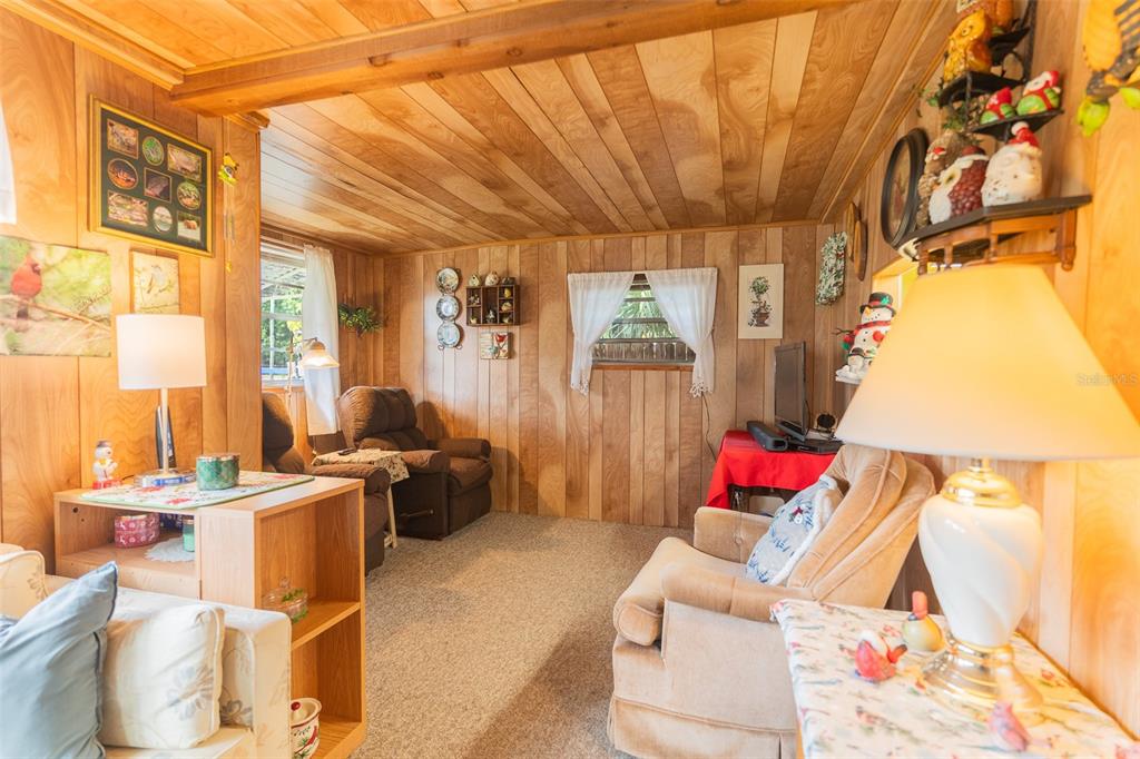 A cozy living room features wood-paneled walls, a vaulted ceiling, and several comfortable armchairs — 28 BASIN STREET, LORIDA, FL