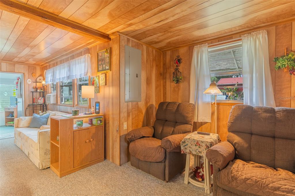 A living room features wood-paneled walls, a vaulted ceiling, two brown recliners, and a sofa — 28 BASIN STREET, LORIDA, FL
