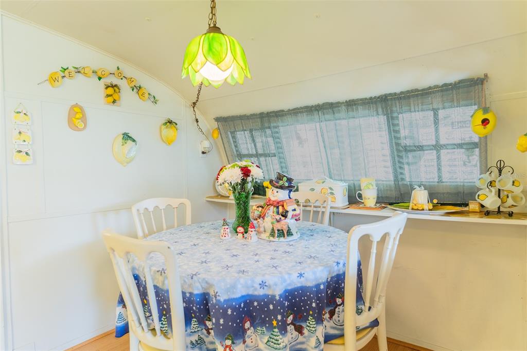 A dining area features a round table with a holiday tablecloth, chairs, and lemon-themed decor — 28 BASIN STREET, LORIDA, FL