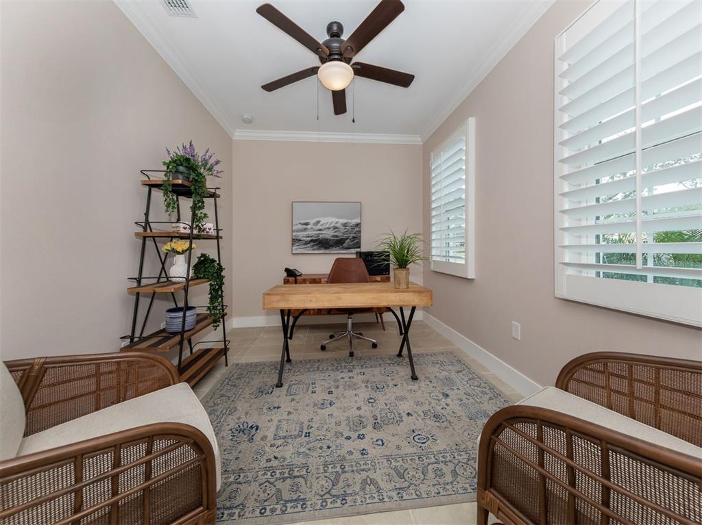 A home office features a wooden desk, two rattan chairs, a rug, and plantation shutters — 938 E VENICE AVENUE, VENICE, FL