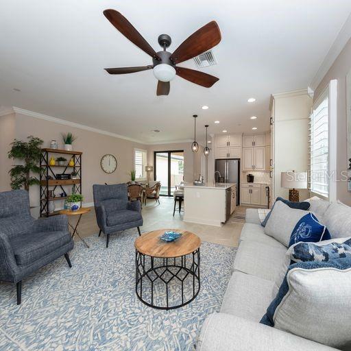 A living room features a ceiling fan, gray armchairs, a round coffee table, and a kitchen — 938 E VENICE AVENUE, VENICE, FL