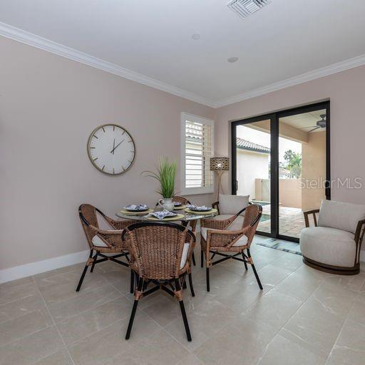 A dining area features a glass-topped table with four wicker chairs and a large wall clock — 938 E VENICE AVENUE, VENICE, FL
