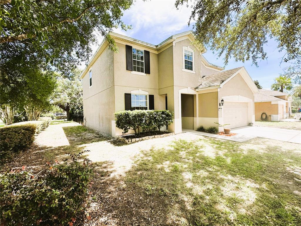 A two-story beige house with a garage, dark shutters, and a front yard — 13850 TRULL WAY, HUDSON, FL