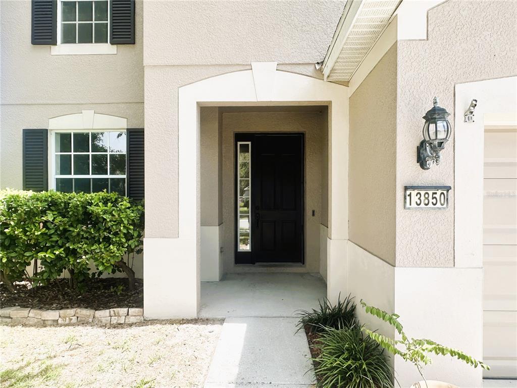 The exterior of a house features a black front door, a walkway, and address numbers — 13850 TRULL WAY, HUDSON, FL