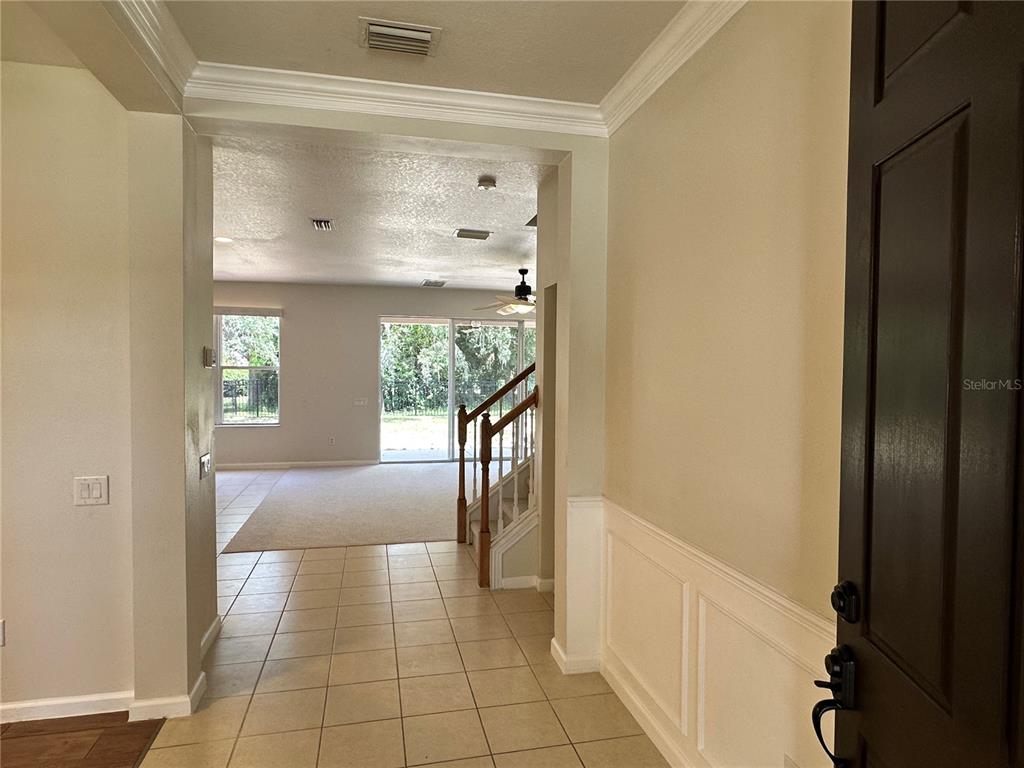 An entryway with tile flooring leads to a living area with carpet and a staircase — 13850 TRULL WAY, HUDSON, FL