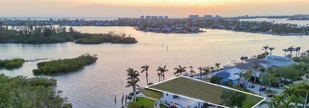 An aerial view of a waterfront house with a highlighted roof and surrounding tropical landscape — 1386 TANGIER WAY, SARASOTA, FL