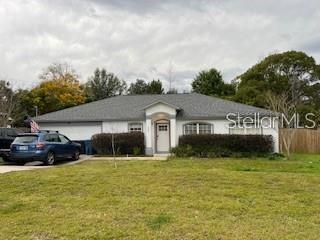 A single-story house with a gray roof, white exterior, and a blue car in the driveway — 330 HICKORY AVENUE, ORANGE CITY, FL