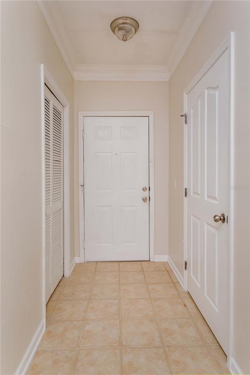 A hallway with tile flooring, a front door, a louvered closet door, and a bedroom door — 12849 MADISON POINT CIRCLE UNIT 201, ORLANDO, FL