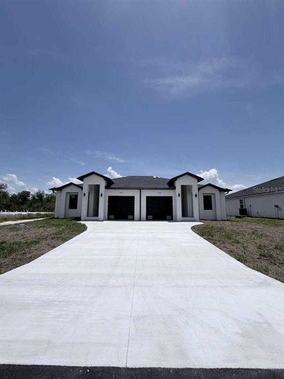 A front view of a modern duplex with two garages and a concrete driveway — 10412 PORT EVERGLADES STREET, PORT CHARLOTTE, FL