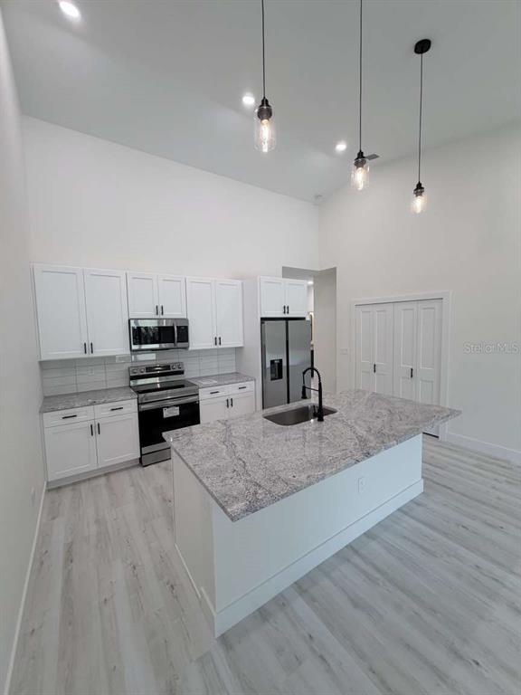 A modern kitchen features white cabinets, granite countertops, a center island, and stainless steel appliances — 10412 PORT EVERGLADES STREET, PORT CHARLOTTE, FL