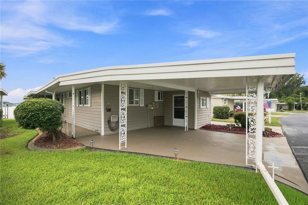 A single-story mobile home with a large covered carport and light-colored horizontal siding — 15 SUNRISE TRAIL, FRUITLAND PARK, FL
