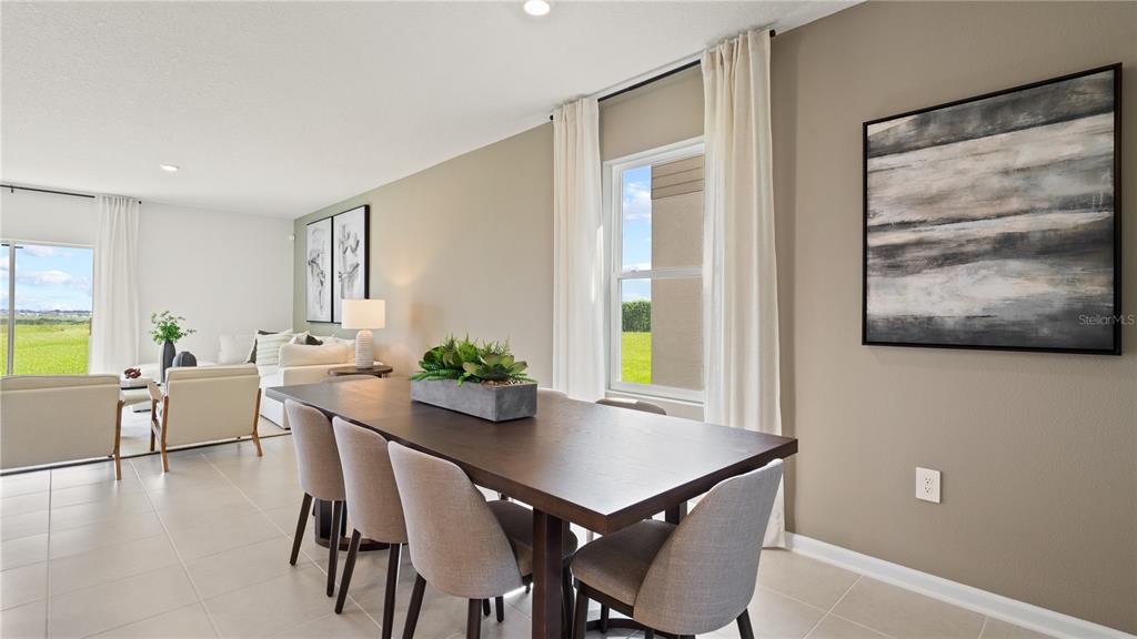 A dining area with a dark wood table and chairs sits adjacent to a living room — 6276 BOTTICELLA BOULEVARD, WINTER HAVEN, FL