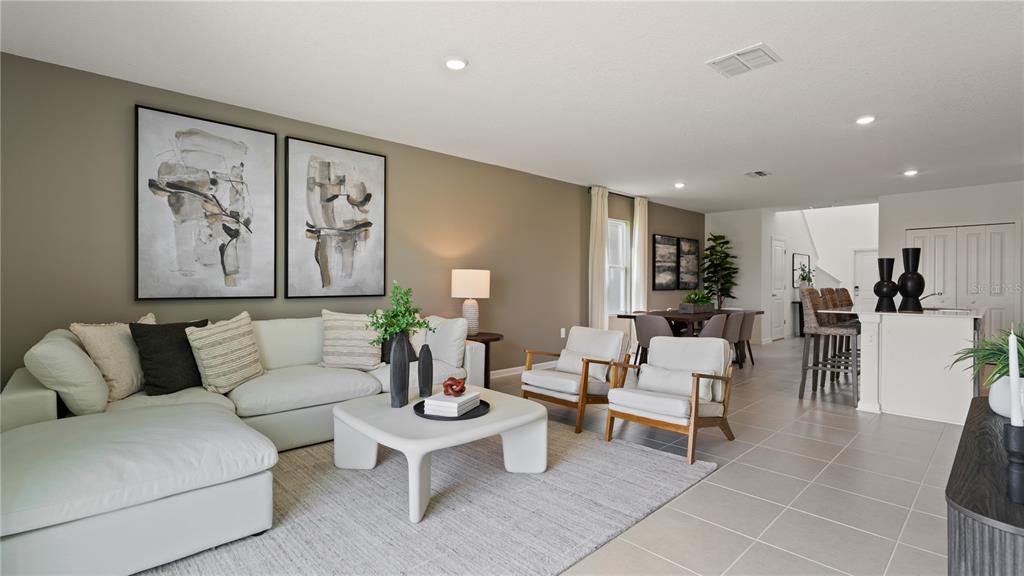 A bright, open-concept living room features a white sectional sofa, two armchairs, and dining area — 6276 BOTTICELLA BOULEVARD, WINTER HAVEN, FL