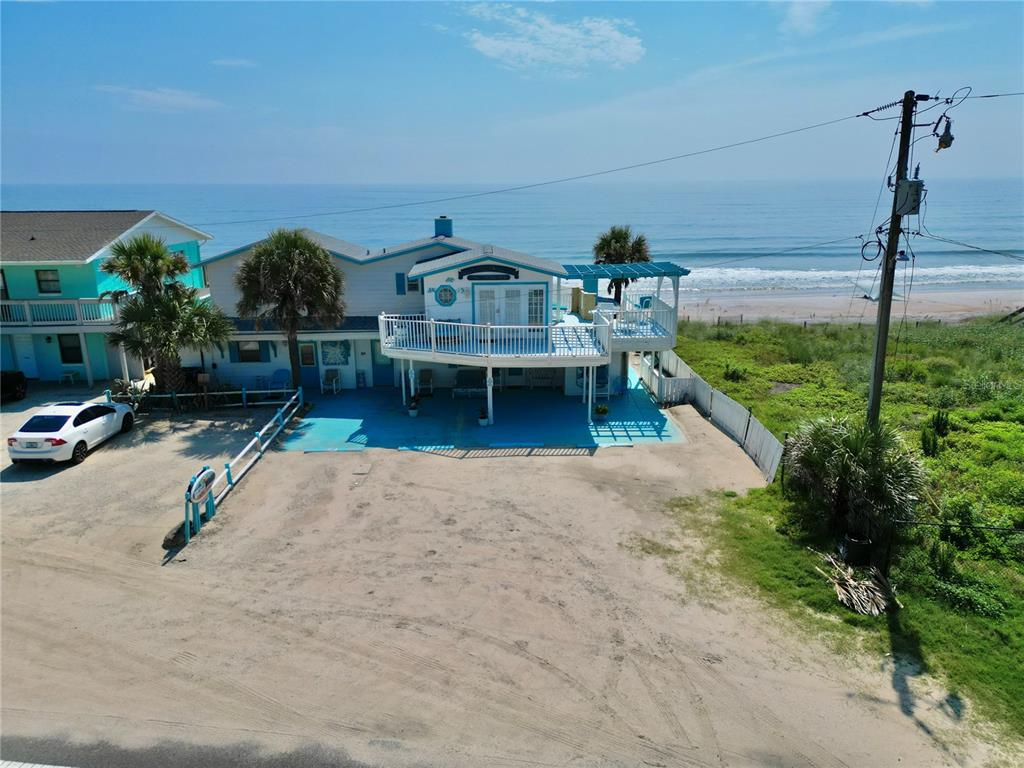 An elevated beach house with a large deck overlooking the ocean and sandy parking area — 2815 S OCEAN SHORE BOULEVARD, FLAGLER BEACH, FL